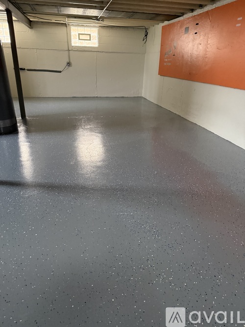 A spacious room with a grey floor and orange wall.