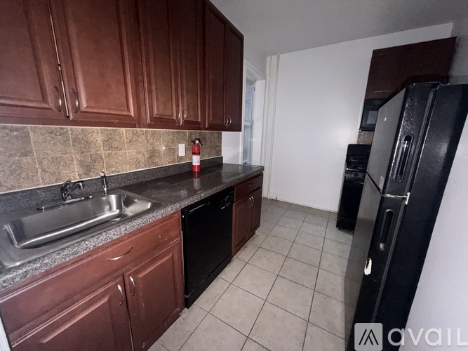 A kitchen with brown cabinets and a black refrigerator.