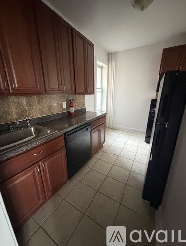 A kitchen with brown cabinets and a black refrigerator.