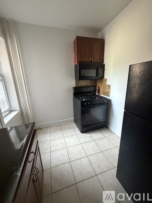 A kitchen with a black refrigerator, black countertops, and a black oven.