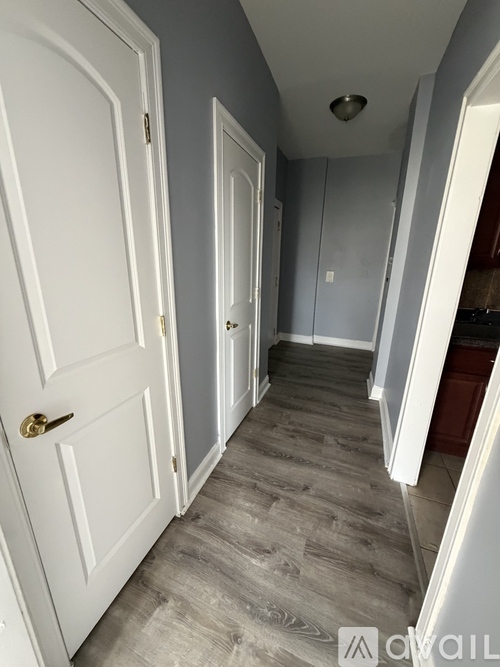 A hallway with a white door on the left and a grey door on the right.