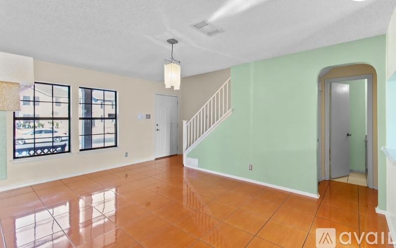 A room with a staircase and a window overlooking a street.