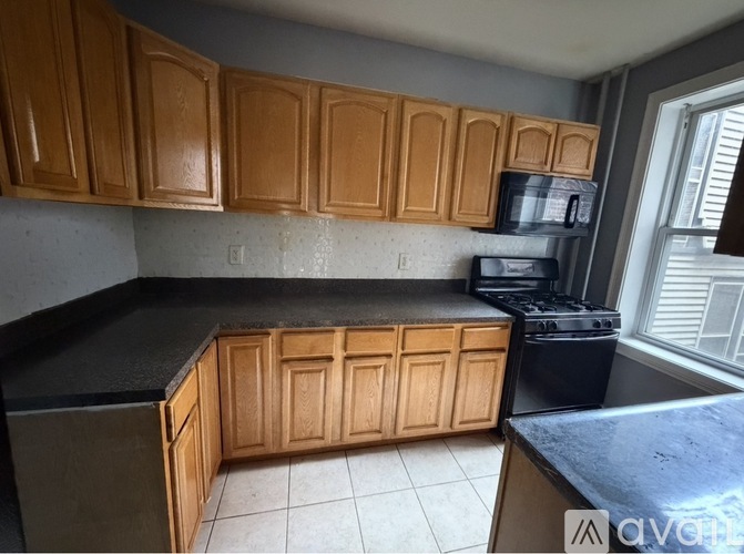 A kitchen with wooden cabinets and black countertops.