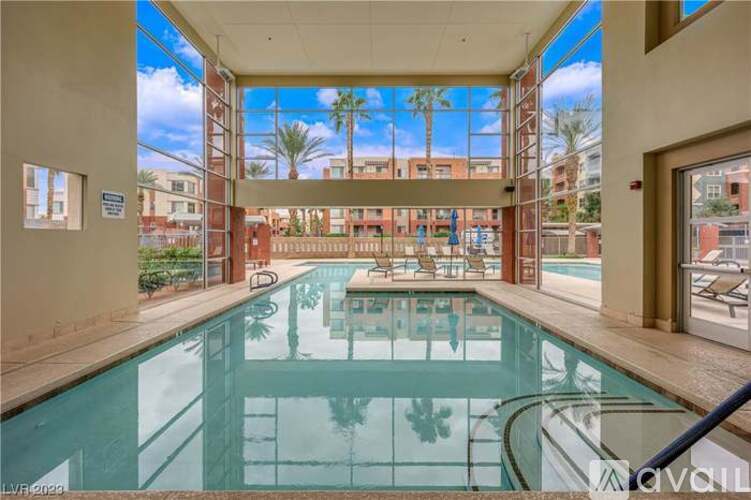 A glass pool in a sunny room with a view of the outside.