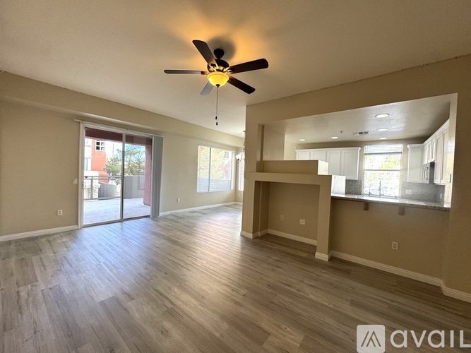 A spacious room with a ceiling fan and sliding glass doors leading to a balcony.