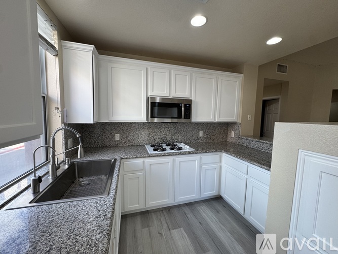 A kitchen with white cabinets and a granite countertop.