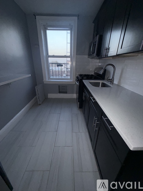 A kitchen with black cabinets and a white sink.