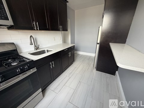 A kitchen with black cabinets and a white sink.