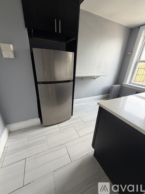 A kitchen with a stainless steel refrigerator and black cabinets.