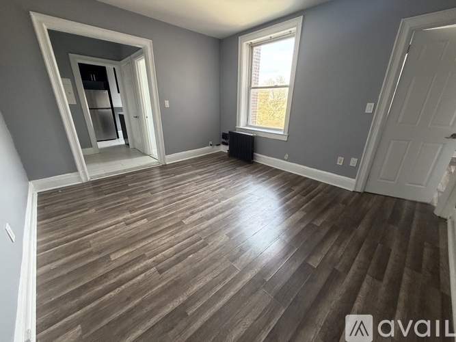 A room with wooden flooring and a large window.