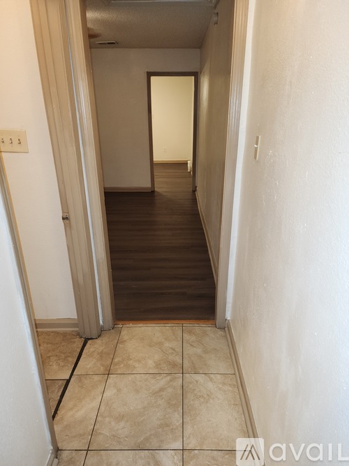 A hallway with a tiled floor and a door on the left.