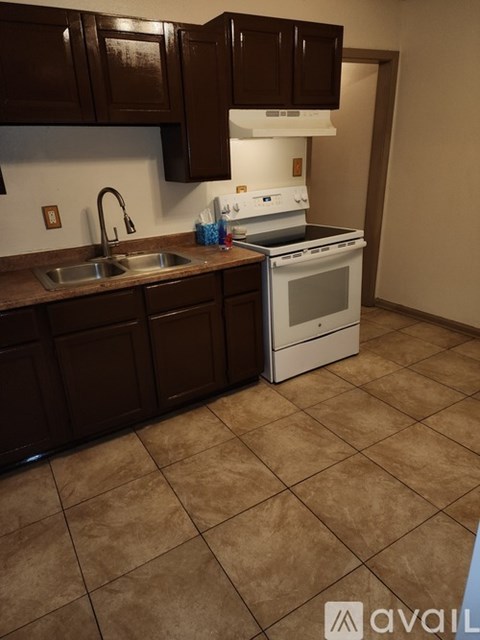 A kitchen with brown cabinets and a white stove.