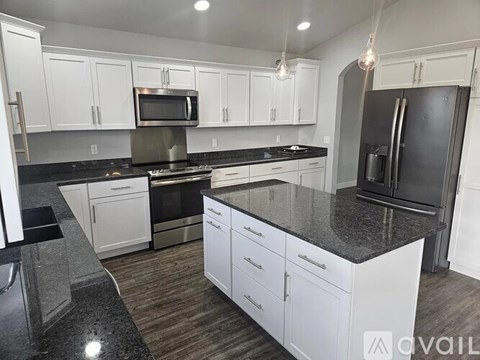 A kitchen with white cabinets and black countertops.