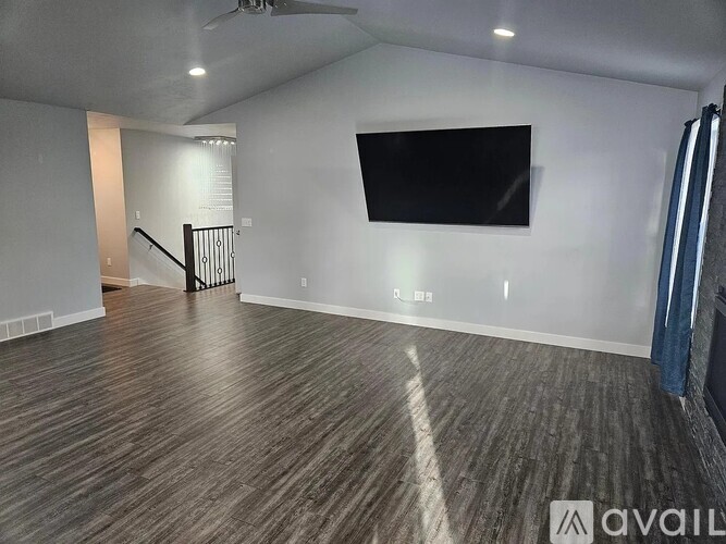 A spacious room with a flat screen TV mounted on the wall and a wooden floor.