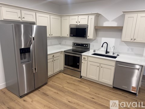 A kitchen with a stainless steel refrigerator and white cabinets.