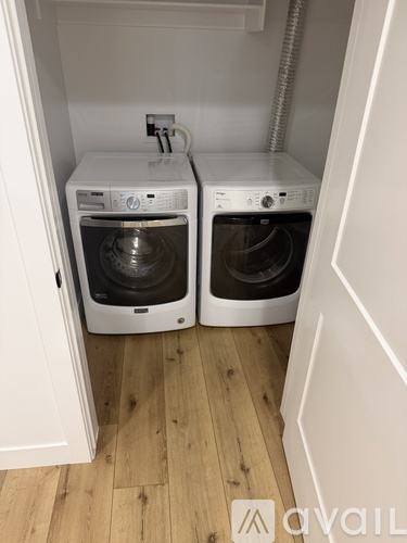 Two white front loading washing machines in a small laundry room.