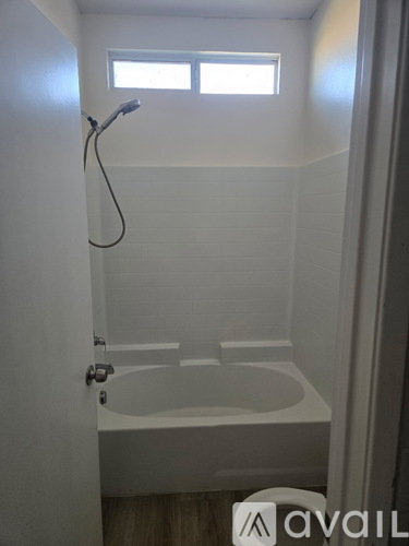 A white bathroom with a tub and a window.