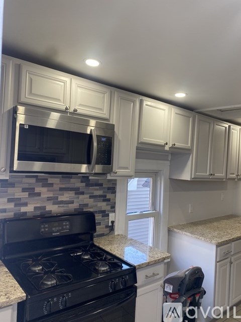 A kitchen with a black stove top oven and white cabinets.