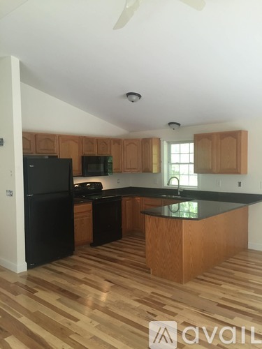 A kitchen with wooden floors and a black countertop.