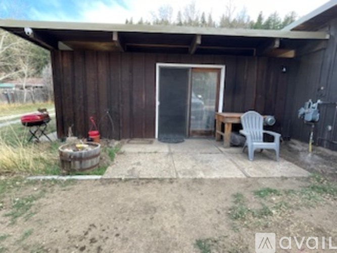 A wooden shed with a door and a window, and a chair outside.