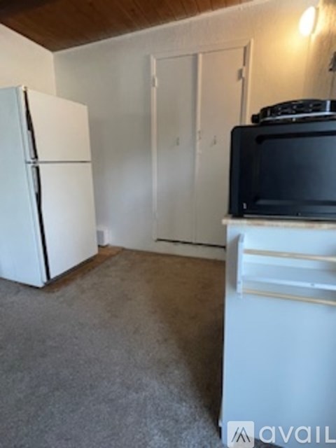 A kitchen with a white fridge and a black microwave.
