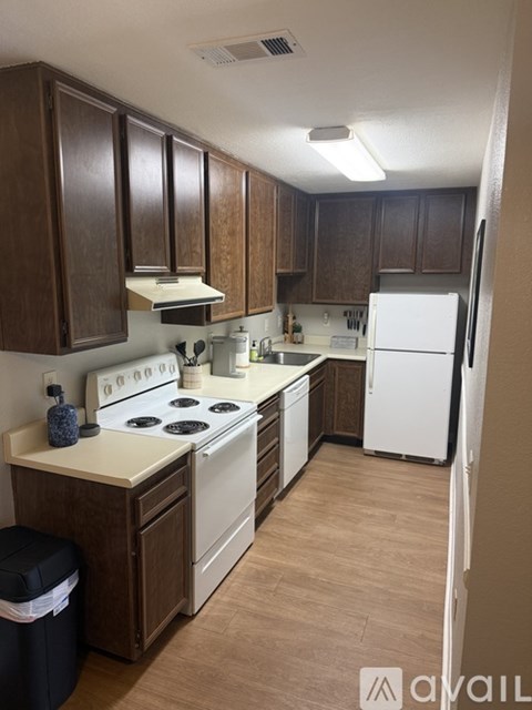 A kitchen with brown cabinets and white appliances.