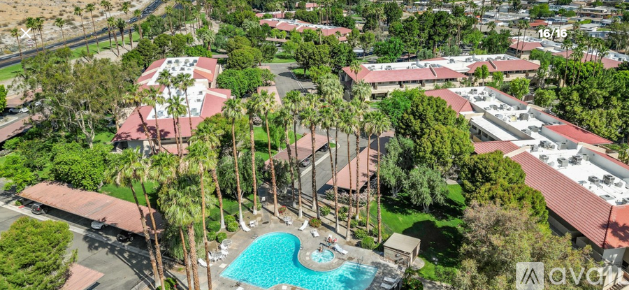 An aerial view of a resort with a swimming pool surrounded by palm trees.
