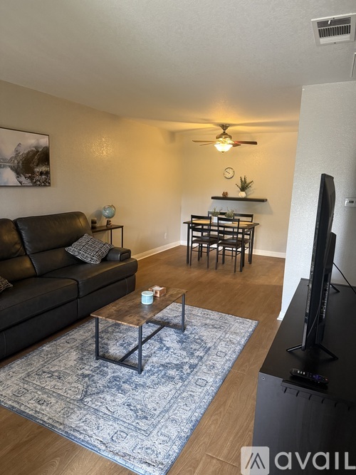 A living room with a black leather couch, a wooden coffee table, and a flat-screen TV.