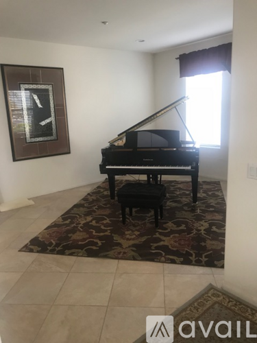 A black grand piano sits in a room with a framed picture on the wall.