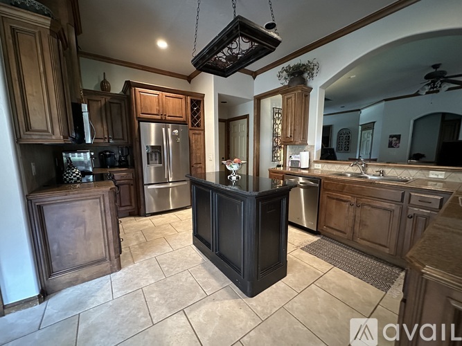 A kitchen with wooden cabinets and a black island.