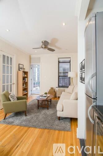 A living room with a green chair, a white sofa, and a wooden coffee table.