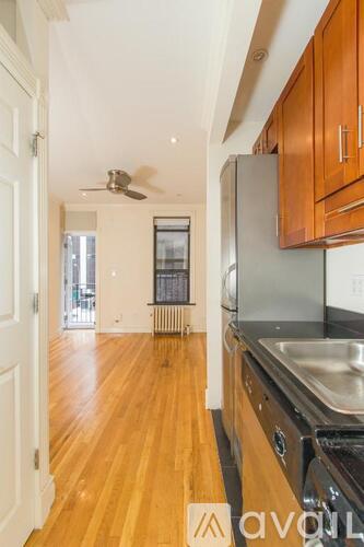 A kitchen with wooden floors and a stainless steel refrigerator.