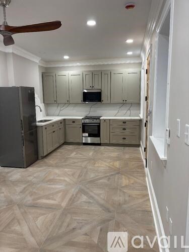 A kitchen with a patterned floor and a ceiling fan.