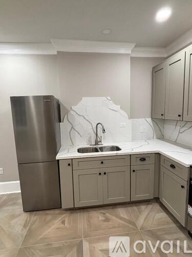 A kitchen with a sink, refrigerator, and cabinets.