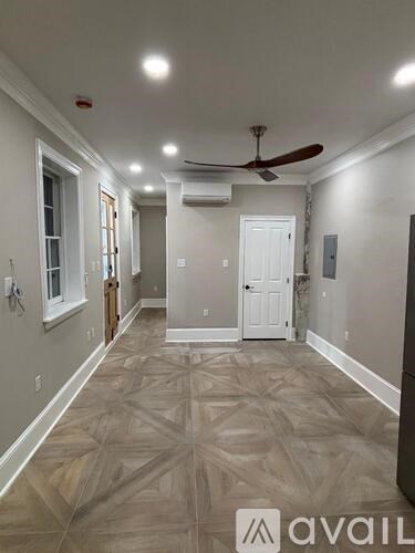 A long hallway with a fan and a door at the end.