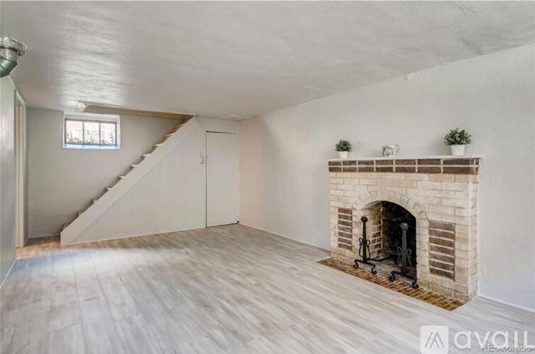 A spacious room with a fireplace and wooden flooring.