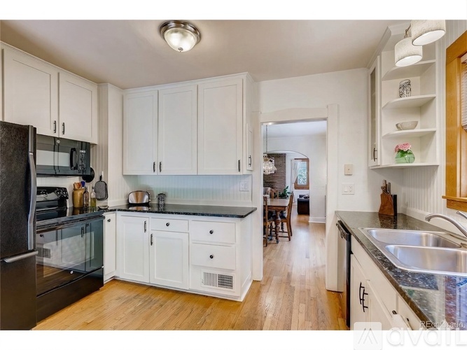 A kitchen with white cabinets and a black refrigerator.