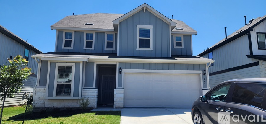 A two-story house with a garage and a car parked in front.
