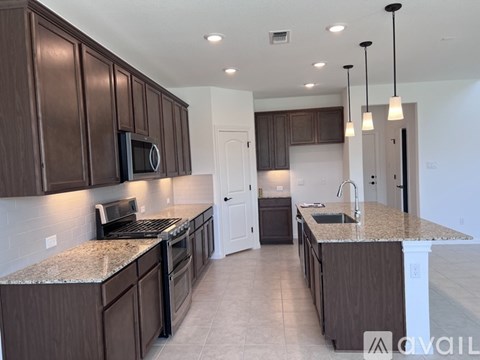 A kitchen with brown cabinets and granite countertops.