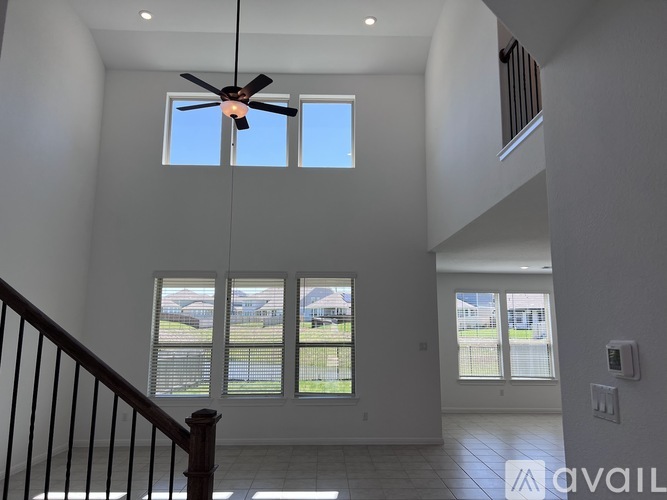 A spacious living room with a ceiling fan and large windows.