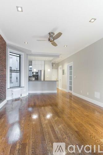 A spacious room with wooden floors and a ceiling fan.