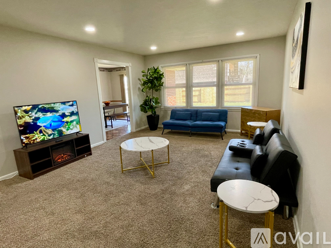 A living room with a television, a blue couch, and a white coffee table.