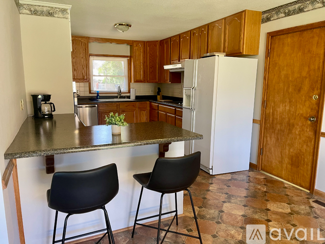 A kitchen with a granite countertop and two black chairs.