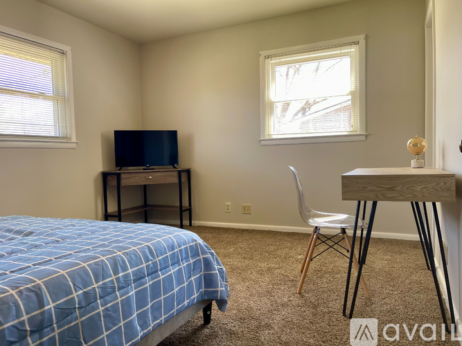 A bedroom with a bed, desk, and chair.