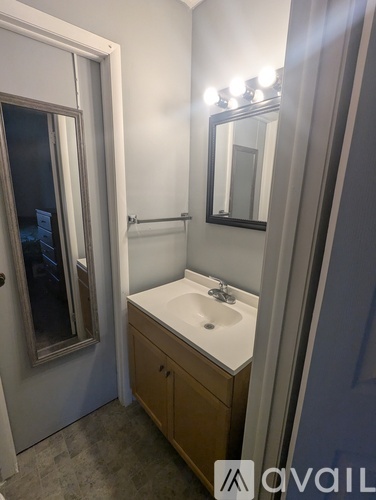 A bathroom with a sink, mirror, and cabinet.