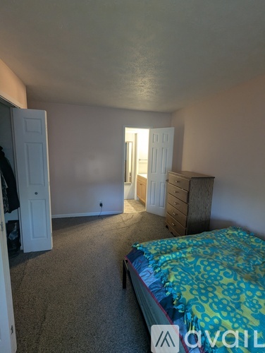 A bedroom with a bed, dresser, and two doors.