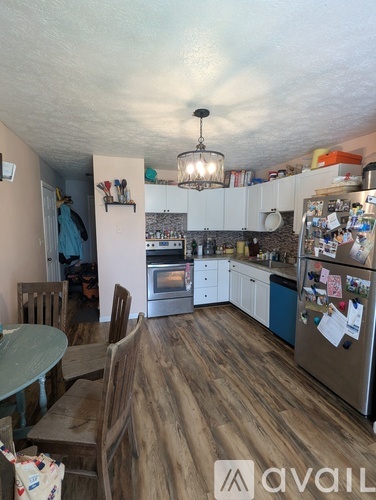 A kitchen with wooden floors and a refrigerator covered in magnets.