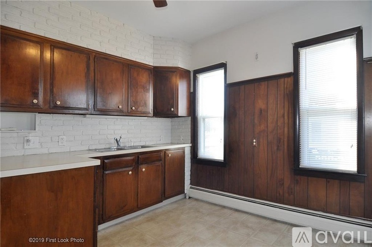 A kitchen with wooden cabinets and a white brick wall.