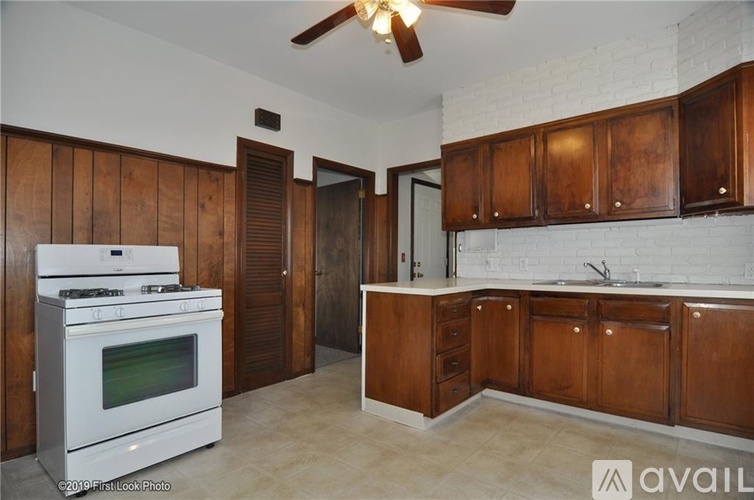 A kitchen with wooden cabinets and a white stove top oven.
