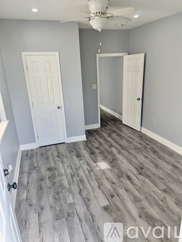 A room with a ceiling fan and two doors.